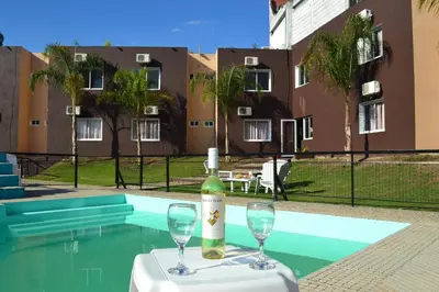 a bottle of wine and two glasses on a table next to a pool at Hotel Montana by CPH in Villa Carlos Paz