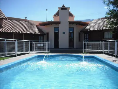 a swimming pool in front of a house at Hosteria Sueños Dorados in Merlo