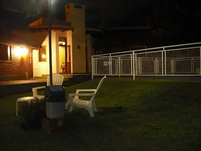 two white chairs sitting in a yard at night at Hosteria Sueños Dorados in Merlo