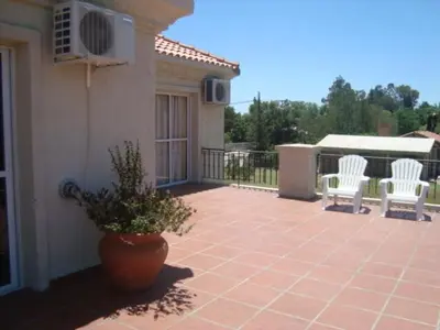 a patio with two white chairs and a potted plant at La Candida Hotel in Merlo