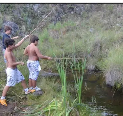 two boys are fishing in a stream with a rod at Cabaña julian in La Cumbrecita