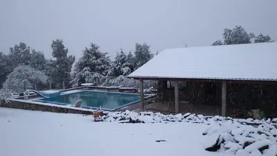 a swimming pool covered in snow next to a house at Cabaña julian in La Cumbrecita