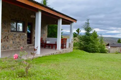a stone house with a table and chairs on a porch at Cabaña julian in La Cumbrecita