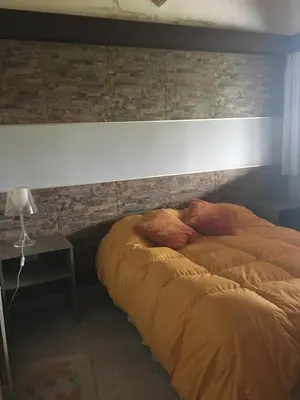 a bed in a bedroom with a brick wall at Cabaña julian in La Cumbrecita