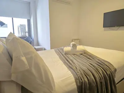 a bedroom with a bed with a alarm clock on it at Departamentos Illia By Lugar in Cordoba