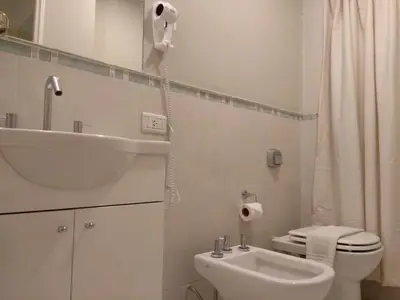 a white bathroom with a sink and a toilet at Departamentos Illia By Lugar in Cordoba