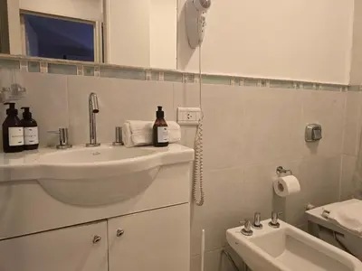 a white bathroom with a sink and a toilet at Departamentos Illia By Lugar in Cordoba