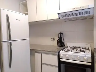 a white kitchen with a stove and a refrigerator at Departamentos Illia By Lugar in Cordoba