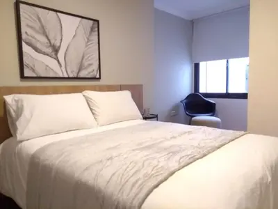 a bedroom with a white bed and a chair at Departamentos Illia By Lugar in Cordoba