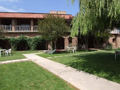 a house with a yard with chairs and tables at Hosteria de la Villa ** in Villa Cura Brochero