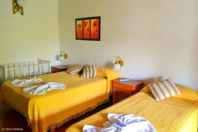 two beds in a room with yellow sheets at Hosteria de la Villa ** in Villa Cura Brochero
