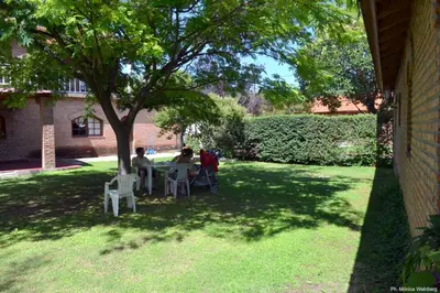 a group of people sitting at a table under a tree at Hosteria de la Villa ** in Villa Cura Brochero