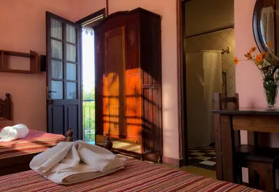 a bedroom with two beds and a door to a balcony at Hostal Las Golondrinas in Bialet Massé