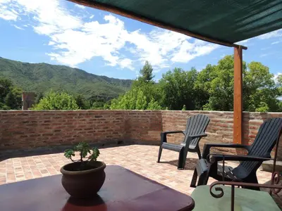 a patio with two chairs and a potted plant at Hostal Las Golondrinas in Bialet Massé