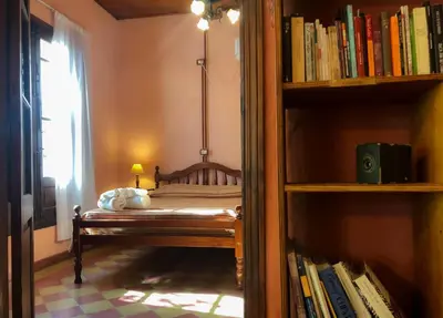 a bedroom with a bed and a book shelf with books at Hostal Las Golondrinas in Bialet Massé