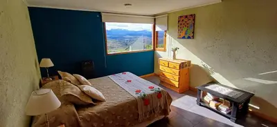 a bedroom with a bed and a large window at Cabaña Esquina Siracusa in Villa Yacanto