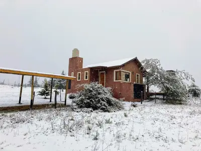 a house in a field with snow on it at Cabaña Esquina Siracusa in Villa Yacanto