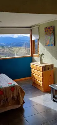 a bedroom with a bed and a large window at Cabaña Esquina Siracusa in Villa Yacanto