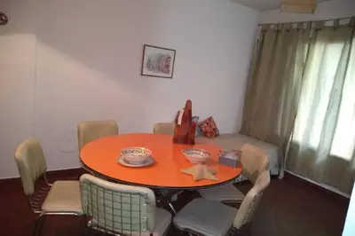 a dining room table and chairs with an orange table at DEPARTAMENTO KRISTINA in Villa Carlos Paz