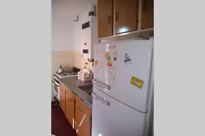 a white refrigerator in a kitchen with wooden cabinets at DEPARTAMENTO KRISTINA in Villa Carlos Paz