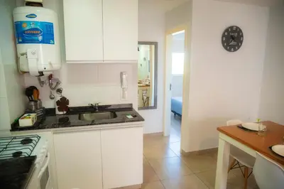 a kitchen with white cabinets and a sink and a table at Río Cuarto Host in Río Cuarto
