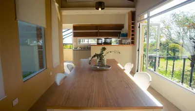 a dining room with a wooden table and some windows at Amardecer - Casa Boutique in Merlo