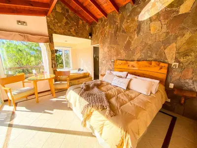 a bedroom with a large bed and a stone wall at Balcones de La Cumbrecita in La Cumbrecita