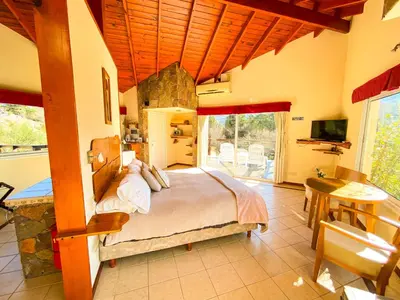 a bedroom with a bed and a table and a television at Balcones de La Cumbrecita in La Cumbrecita