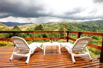 two chairs and a table on a wooden deck at Balcones de La Cumbrecita in La Cumbrecita