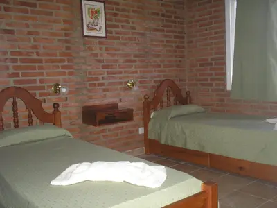 a bedroom with two beds and a brick wall at El Mirador de Nono in Nono