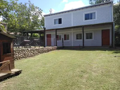 a white house with a stone wall and a yard at Cabañas El Nogal in Villa Anizacate