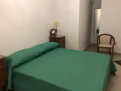 a bedroom with a green bed and a chair at URBANO TAJAMAR in Alta Gracia