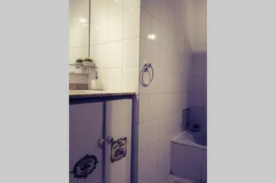 a white tiled bathroom with a shower and a sink at Nuevocentro Modern in Cordoba