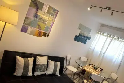 a living room with a black couch and a table and chairs at Nuevocentro Modern in Cordoba