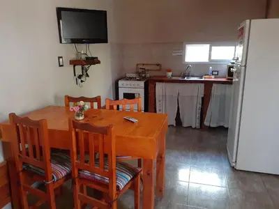 a kitchen with a wooden table with chairs and a refrigerator at Cabañas Ecos del Valle in Los Reartes