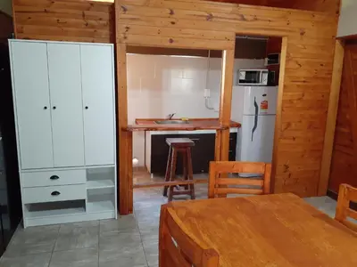 a kitchen with a white refrigerator and a table at Cabañas Ecos del Valle in Los Reartes