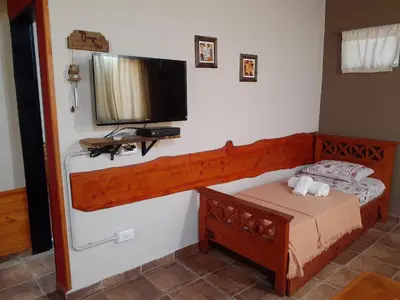 a bedroom with a bed and a flat screen tv at Cabañas Ecos del Valle in Los Reartes
