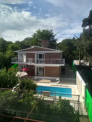 a house with a swimming pool in front of it at Complejo Belu in Santa Rosa de Calamuchita