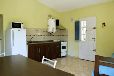 a kitchen with a white refrigerator and a table with a sink at Complejo Belu in Santa Rosa de Calamuchita
