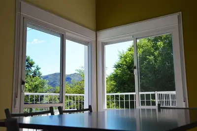 a dining room with two large windows and a table at Complejo Belu in Santa Rosa de Calamuchita