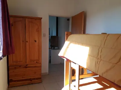 a bedroom with a bed and a wooden cabinet at Alas Mágicas in Villa Yacanto