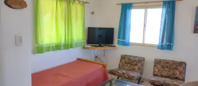a room with a bed and a tv and two chairs at Alas Mágicas in Villa Yacanto