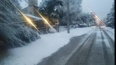 a snow covered street with a house in the background at Departamento Cerro Negro in Villa General Belgrano