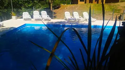 a group of white chairs next to a swimming pool at Departamento Cerro Negro in Villa General Belgrano