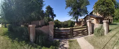 a fence with a wooden gate in front of a house at Departamento Cerro Negro in Villa General Belgrano