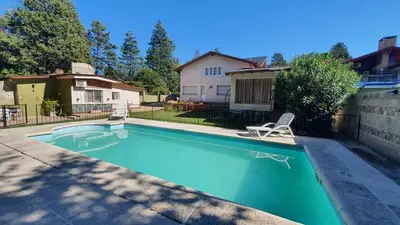 a swimming pool with a chair and a house at Teilen in Villa General Belgrano