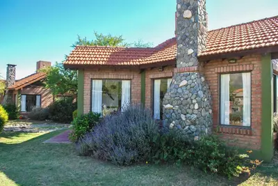 a brick house with a stone chimney and a yard at La Morada in Merlo