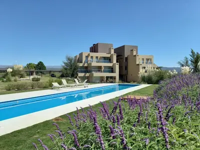 a villa with a swimming pool and purple flowers at Apart Carlos Paz Golf Country Club in Villa Carlos Paz