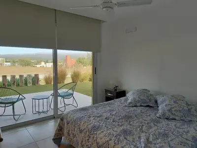 a bedroom with a bed and a patio with chairs at Apart Carlos Paz Golf Country Club in Villa Carlos Paz