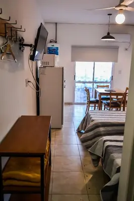 a room with two beds and a refrigerator and a table at Dpto con Balcón- Rafael Nuñez - Cerro de las Rosas in Cordoba